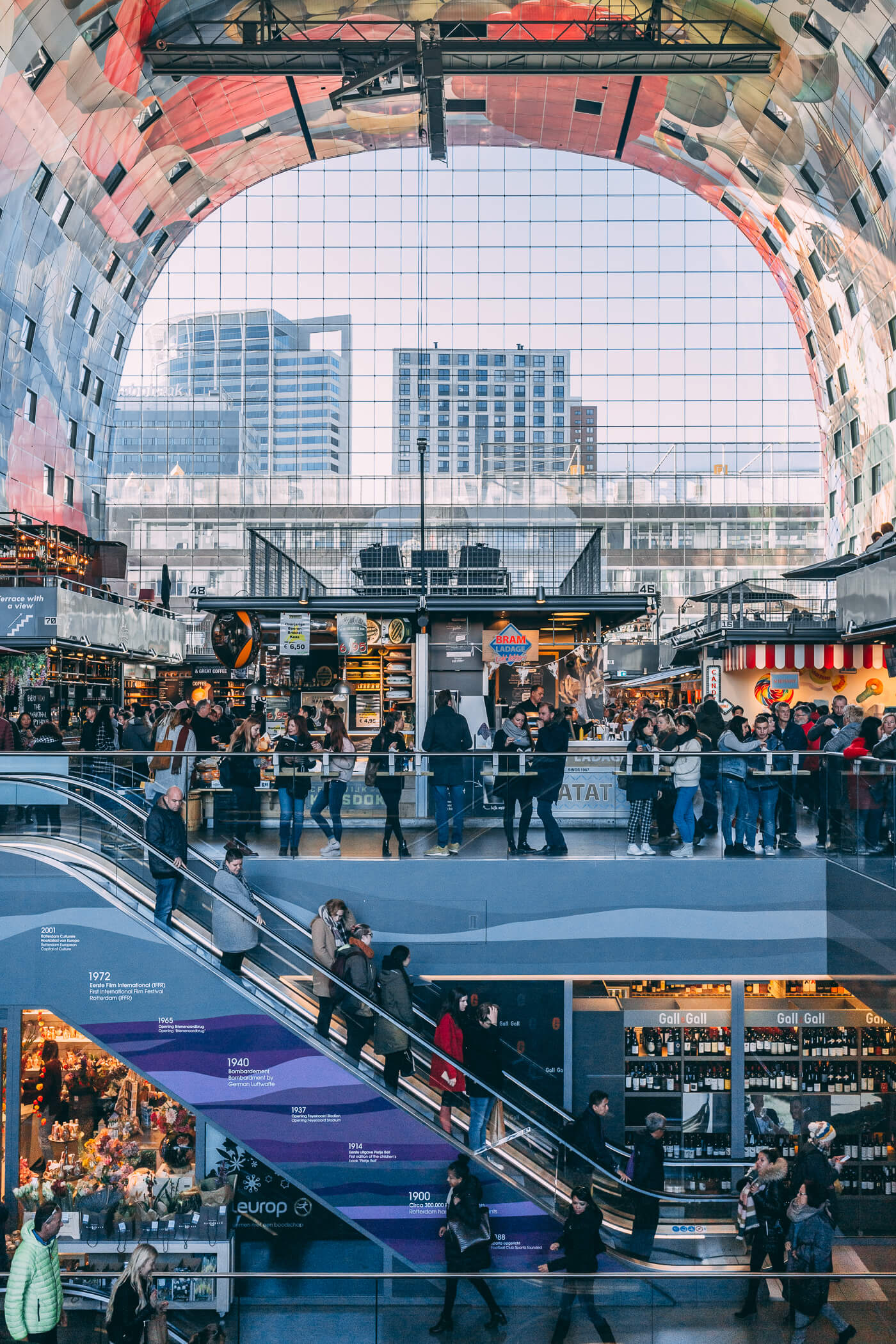 The busy interior of De Markthal full of shoppers - an incredible combination of colourful indoor market and luxury housing in Rotterdam, Netherlands.