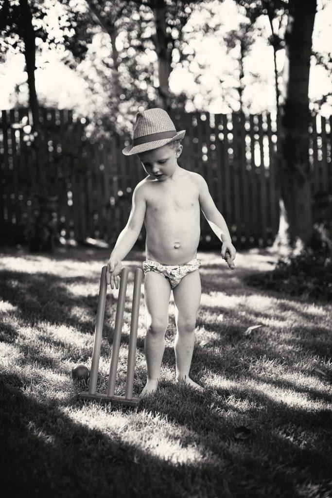Black & white portrait of a young boy playing cricket