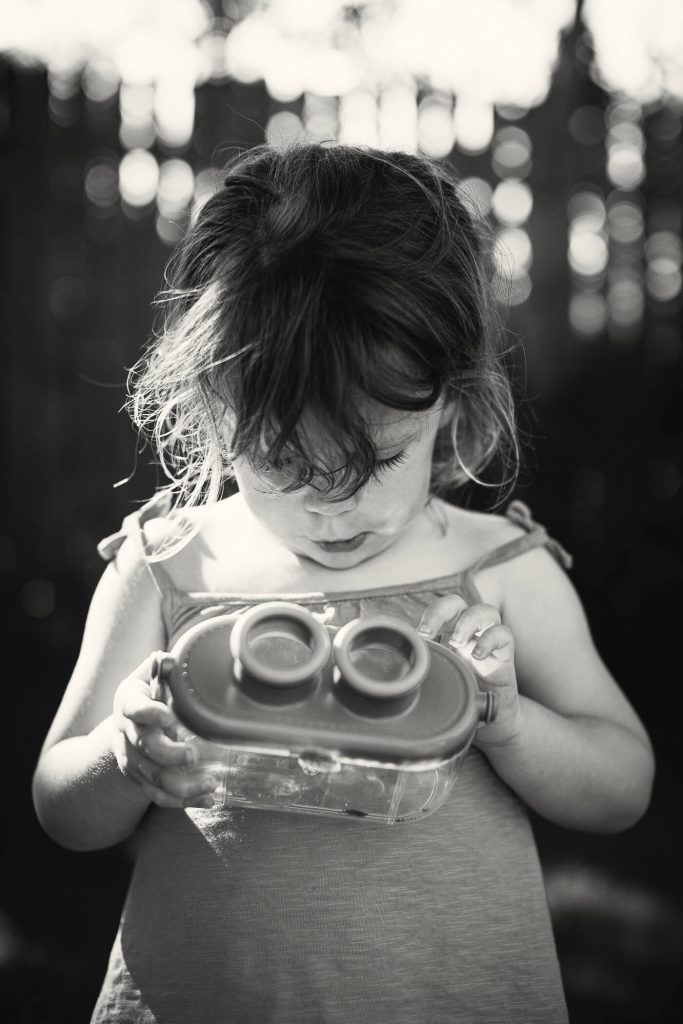Black & white portrait of a young girl looking at a bug