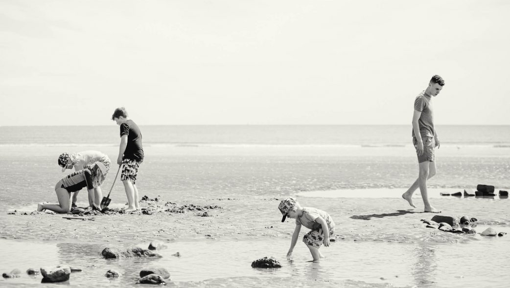 Black & white photograph of children playing on the beach at Filey seafront, UK