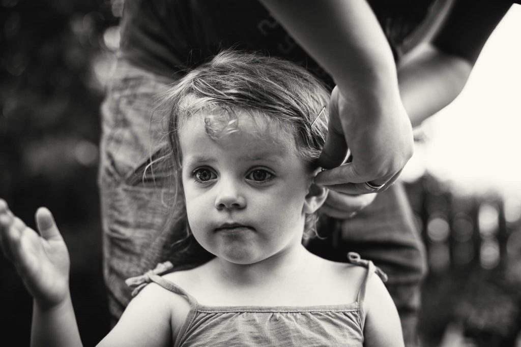Black & white photo of a young girl having her hair tied back