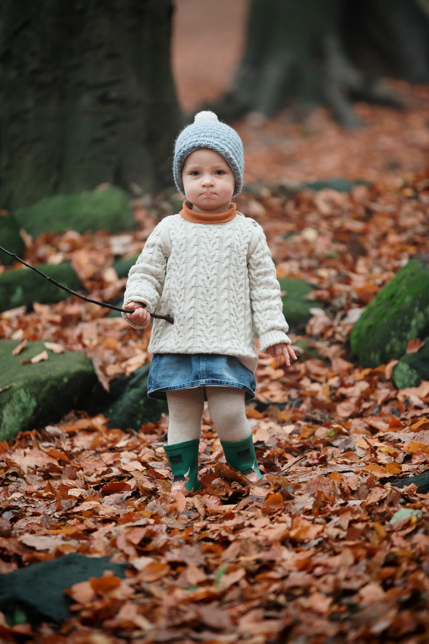 Photograph of a young girl surrounded by fallen autumn leaves