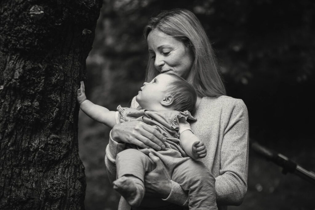 Black and white portrait of a mother and her young daughter by a tree