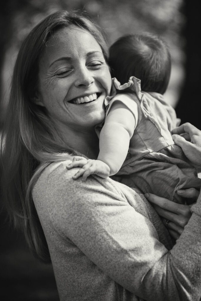 Photograph of a mother smiling as she holds her young daughter