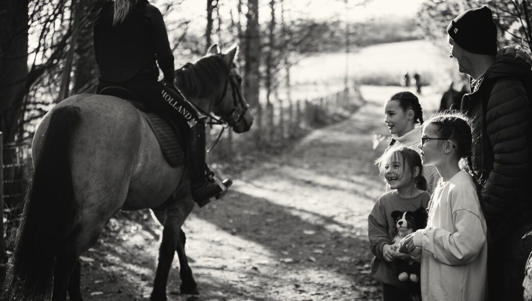 Photograph of a family watching a horse ride past
