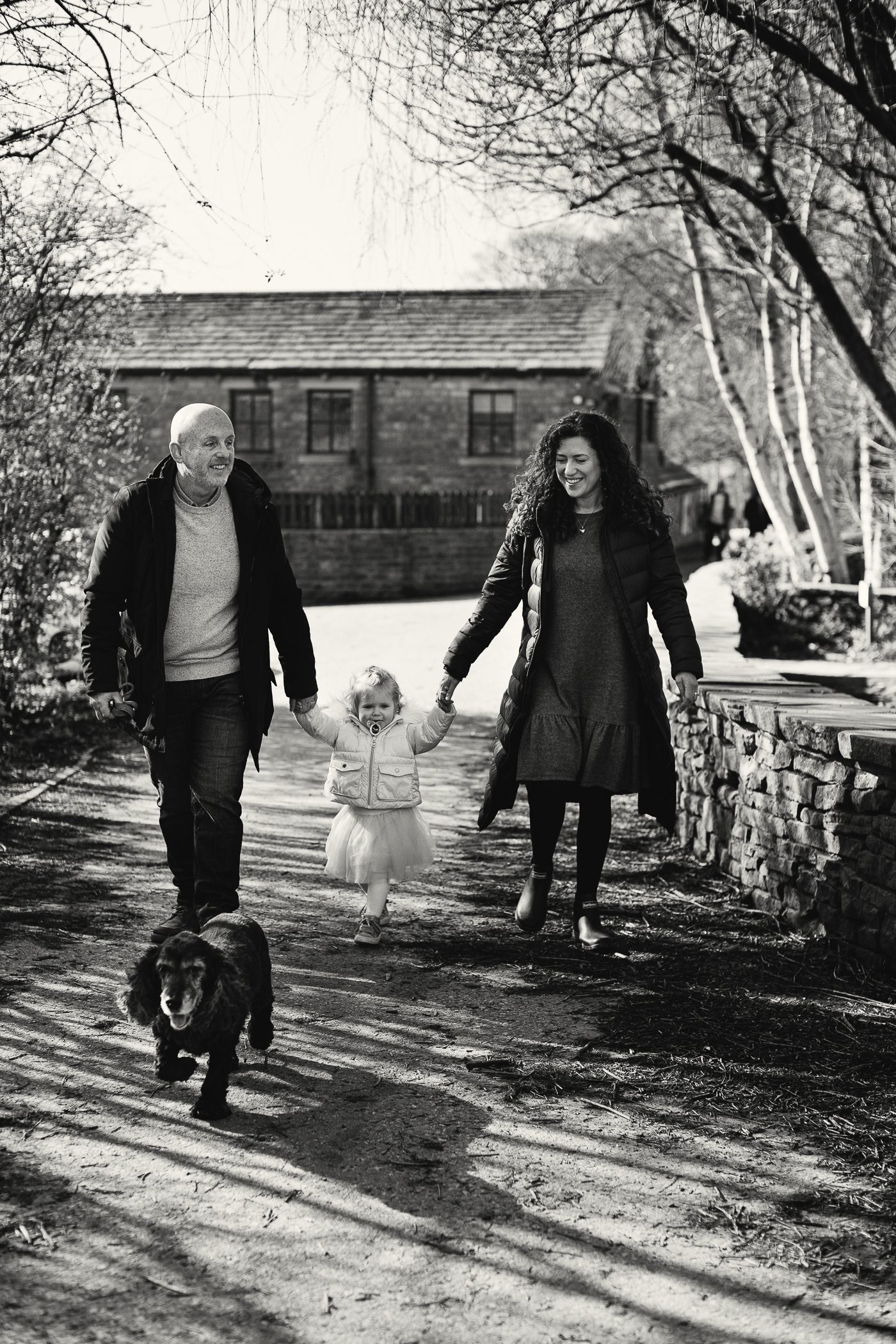 Family photography - couple walking hand in hand with toddler and their dog