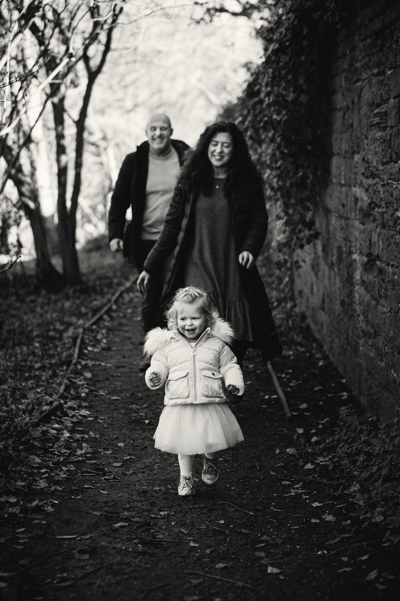Black and white photo of a young girl walking in front of her parents