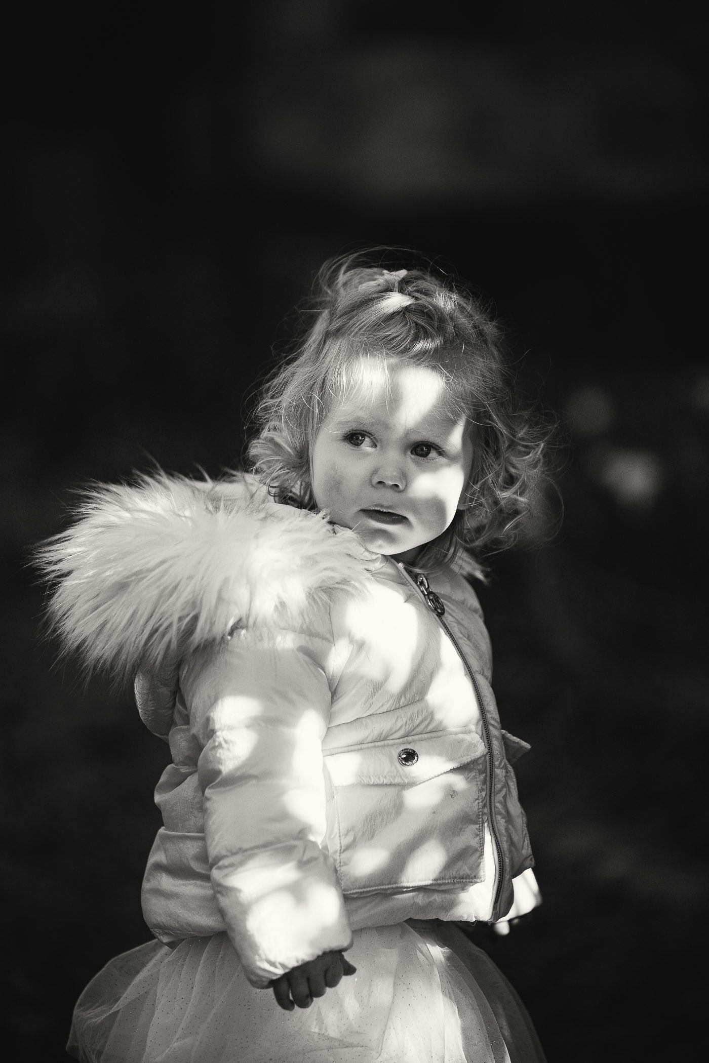 Fine art black and white portrait of a young girl in dappled light